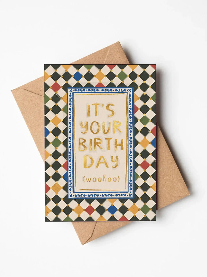 Trendy birthday greetings card featuring 'It's your birthday (woohoo)' in gold foil with harlequin check background.